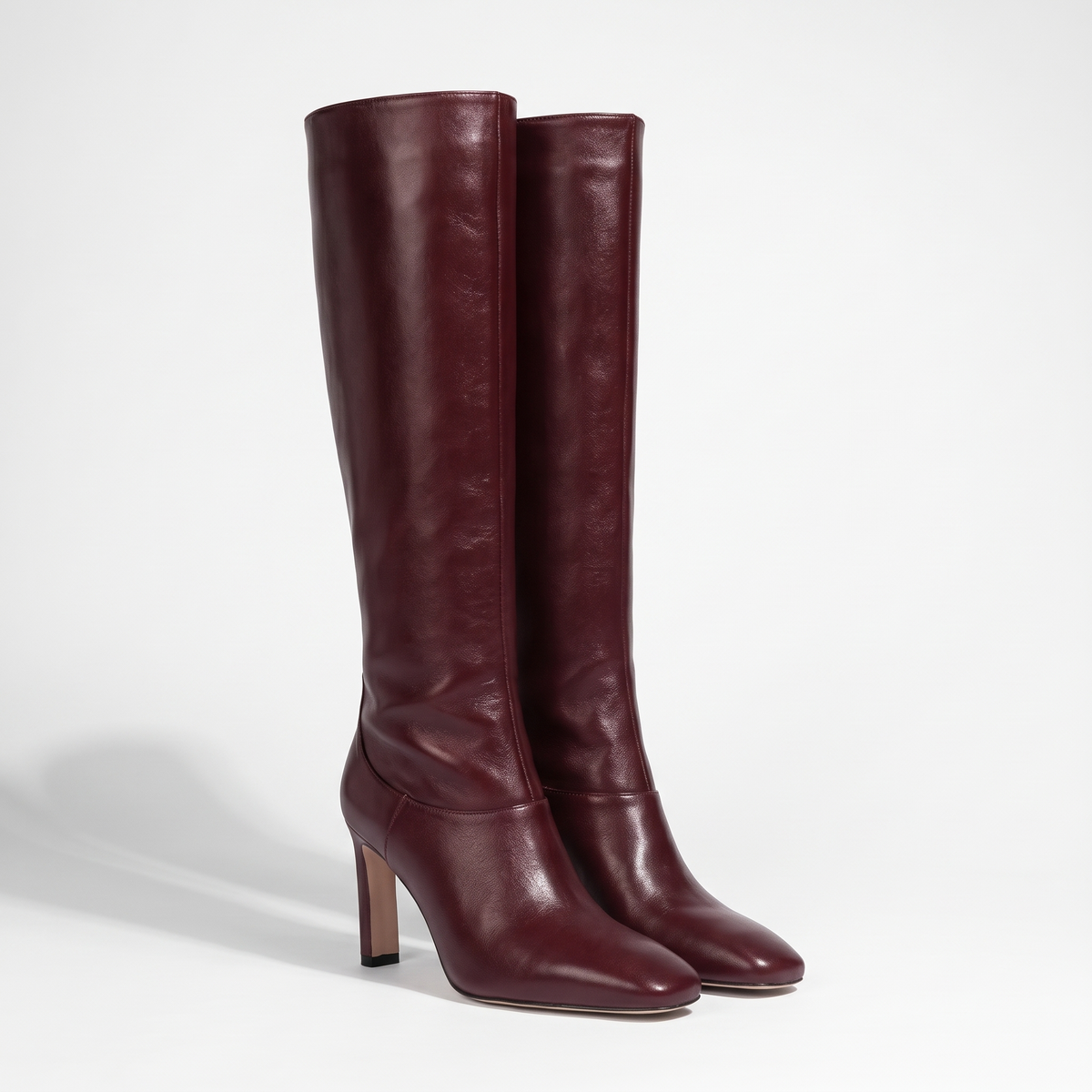 VogueStiletto elegant knee-high bordeaux leather boots with pointed toe and stiletto heel, studio product photo